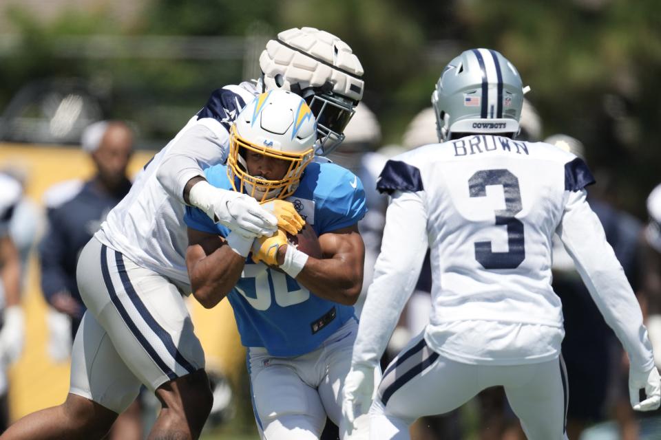 Los Angeles Chargers running back Austin Ekeler (30) is defended by Dallas Cowboys linebacker Micah Parsons (11) and cornerback Anthony Brown (3) during joint practice at Jack Hammett Sports Complex.